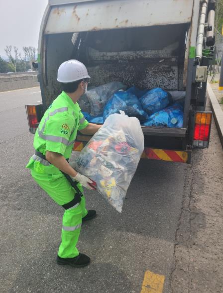 구로구 환경미화원이 근력증강 착용형(웨어러블)로봇을 착용하고 쓰레기봉투를 청소차로 옮기고 있다.