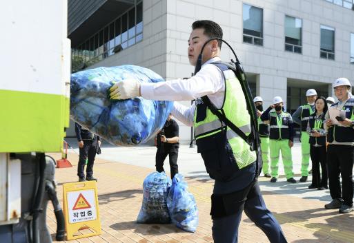 오언석 도봉구청장이 ‘입는 로봇’을 입고 쓰레기를 청소차에 옮기고 있다
