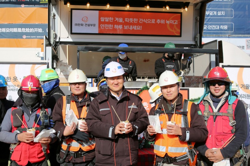 한화 건설부문 김우석 대표이사(가운데)가 건설현장 근로자들과 함께 ‘찾아가는 겨울간식차’의 호빵과 어묵을 즐기고 있다.(사진=한화 건설부문)