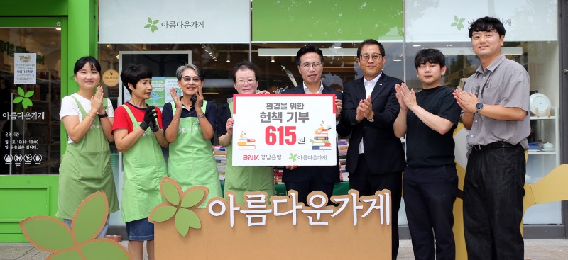 BNK경남은행 이명훈 부장(사진 오른쪽 네번째)이 아름다운가게 경남본부 정윤희 본부장에게 헌책을 전달한 뒤 단체 기념촬영을 하고 있다. 사진=BNK경남은행