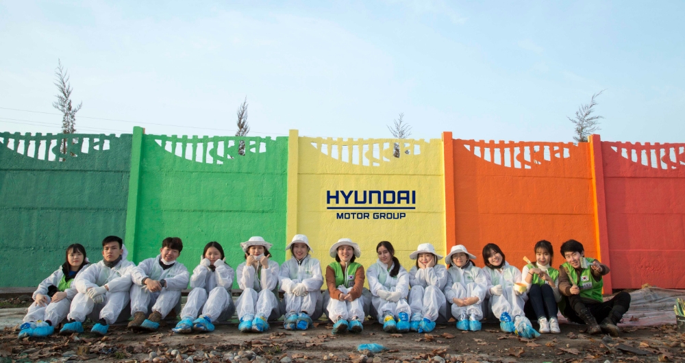 22기 봉사단원들이 우즈베키스탄 고려인 마을인 아흐마드 야싸비의 초등학교에서 벽화 그리기 봉사활동 중 기념사진을 찍고 있는 모습.(사진=현대자동차)