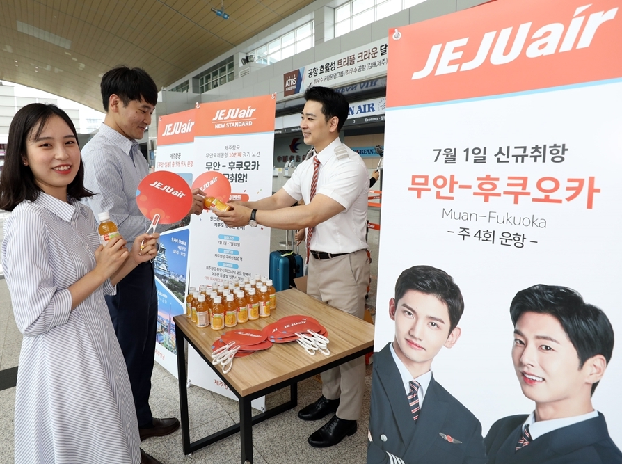 제주항공 승무윈이 7월1일 오후 무안국제공항에서 무안~후쿠오카 탑승객들에게 제주산 감귤 과즙음료와 부채를 건네주고 있다. (사진=제주항공)