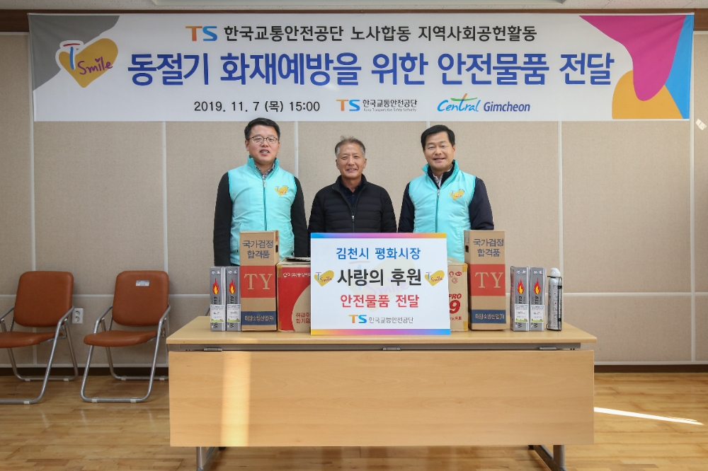 한국교통안전공단 권병윤 이사장(사진 우측) 및 노동조합 박원덕 위원장(사진 좌측)이 김천 평화시장 상인들에게 화재예방을 위한 안전용품(소화기)을 전달하고 있다.(사진=한국교통안전공단)