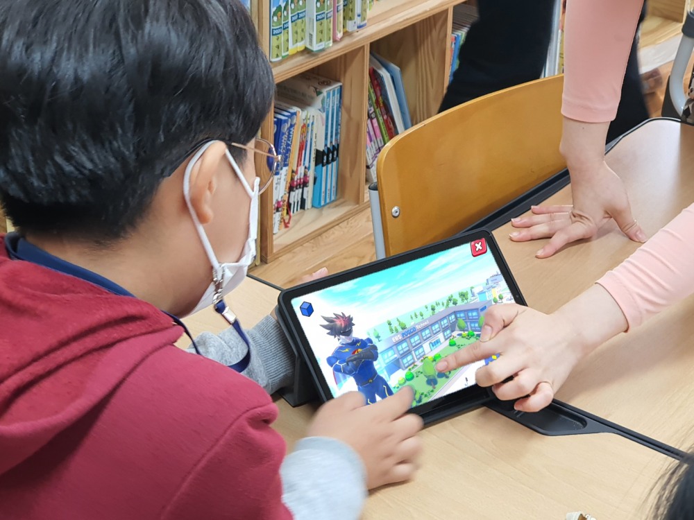 초등학생이 「번개맨과 친환경 번개파워」 어플리케이션에서 포스코의 스마트 하우징(모듈러) 기술을 활용해 무너진 학교를 재건하고 있는 장면.(사진=포스코)