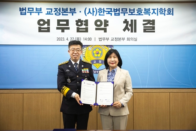 신용해 교정본부장과 양회경 학회장이 27일 법무부 교정본부회의실에서 업무협약서를 내보이며 기념촬영.(사진제공=한국법무보호복지학회)