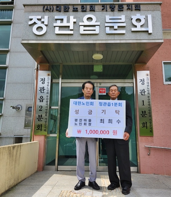 정관읍 평전마을 최희수 노인회장(좌측)이 김도봉 정관읍1분회장(우측)에게 성금을 기탁하고 기념촬영.(사진제공=부산 기장군)