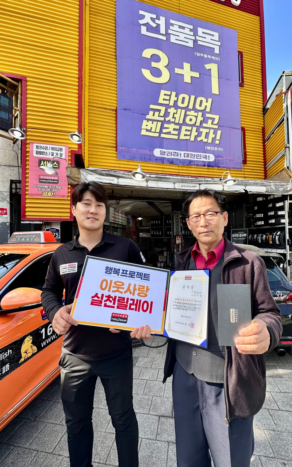 서울시 관악구 심림동에 위치한 타이어뱅크 신림점에서 신림점 조영빈 사업주(좌)와 GK33 특별봉사단 길리섭 단장(우)이 기념 촬영을 하고 있다.(사진=타이어뱅크)