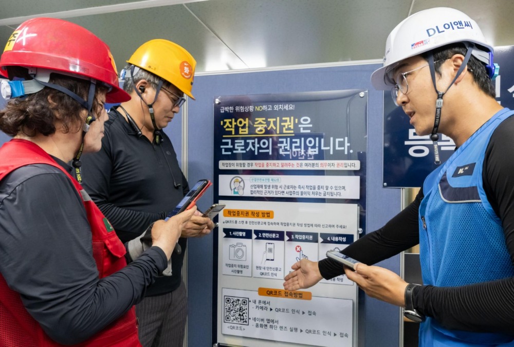 DL이앤씨 현장 안전관리자(우측 첫번째)가 현장 근로자들에게 안전신문고 접속 및 작업중지권 사용법에 대해 설명하고 있다.(사진=DL이앤씨)