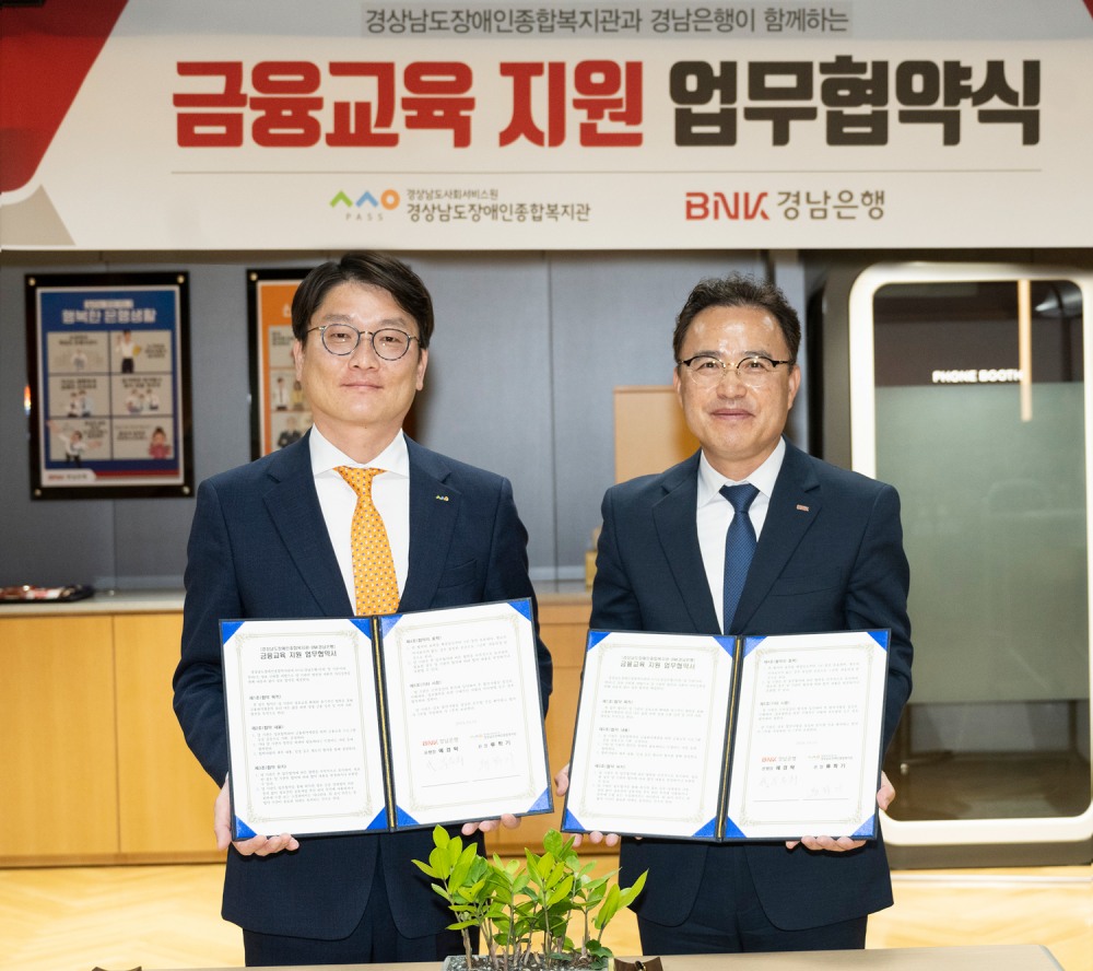 BNK경남은행 박두희 상무(사진 오른쪽)와 경상남도장애인종합복지관 류학기 관장이 ‘금융교육 지원 업무 협약’을 체결하고 있다. 사진=BNK경남은행