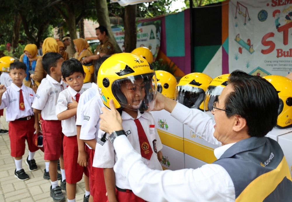안전모 전달식에 참여한 KB손해보험 조정래 인니법인장이 학생들에게 안전모를 씌워주고 있다. 사진=KB손해보험