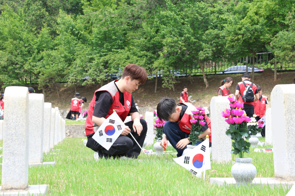 롯데건설 ‘샤롯데 봉사단’이 묘비 옆에 태극기를 꽂고 있다.(사진=롯데건설)