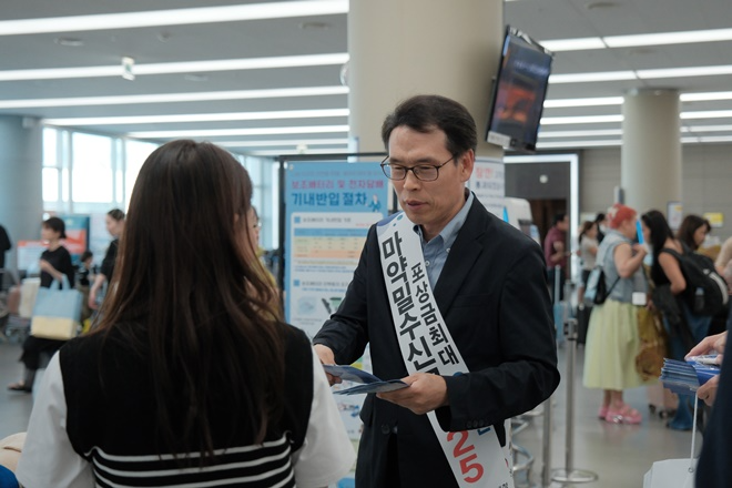 문흥호 김해공항세관장이 여행객들에게 마약류 밀반입 근절 홍보 물품을 나눠주고 있다.(제공=김해공항세관)