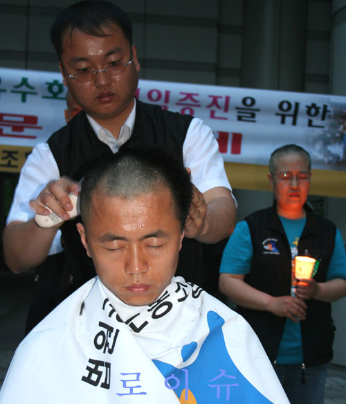 ▲김대열서울가정지부장이삭발투쟁에동참하고있다.▲노조간부들의삭발식이거행하는동안촛불시위에참가한법원직원들이민중가요를부르며격려하고있다.