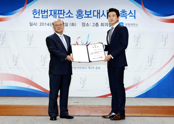 ▲8일헌법재판소2층회의실에서배우김명민이박한철헌법재판소장으로부터홍보대사위촉장을수여받고있다.(사진제공=헌법재판소)