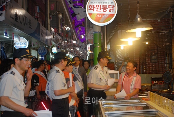 ▲권기선부산경찰청장이범죄예방홍보전단지를나눠주며상인과대화를나누고있다.