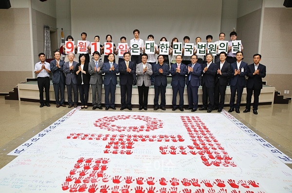 ▲전국19개지방법원수에맞춰19개글자를제작하고창원지법은19개글자중‘원’을담당하는손도장찍기행사를갖고기념촬영.(사진제공=창원지법)