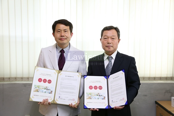 부산구치소 이희식 의료과장(사진왼쪽)이 라인업치과 오창용 대표와 업무협약서를 내보이며 기념촬영.