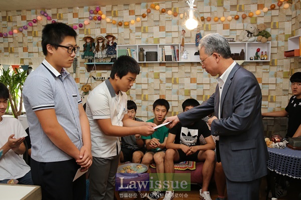 강동명 회장이 우수학생 2명에게 장학금을 전달하고 격려하고 있다.