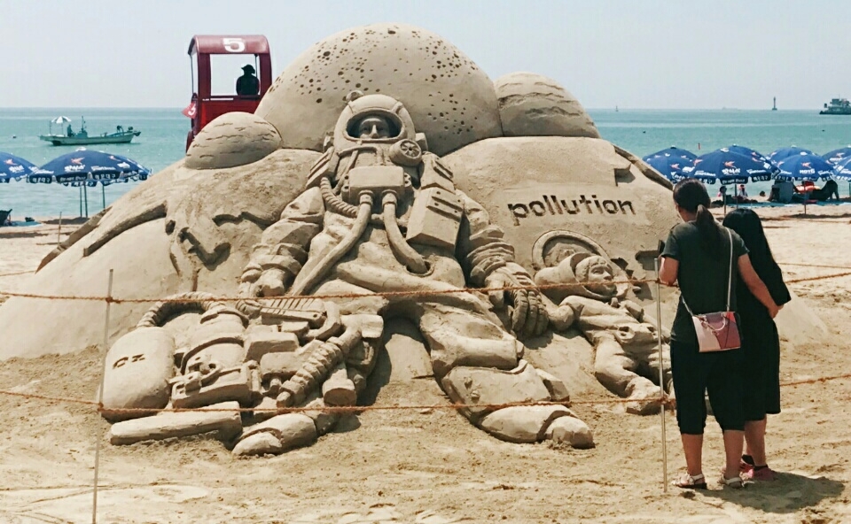 ‘2017 한국필립모리스 바다사랑 캠페인’의 일환으로 부산 송정 해수욕장에 마련된 환경 주제 모래 조형 작품을 감상하는 피서객의 모습.(제공=한국필립모리스)
