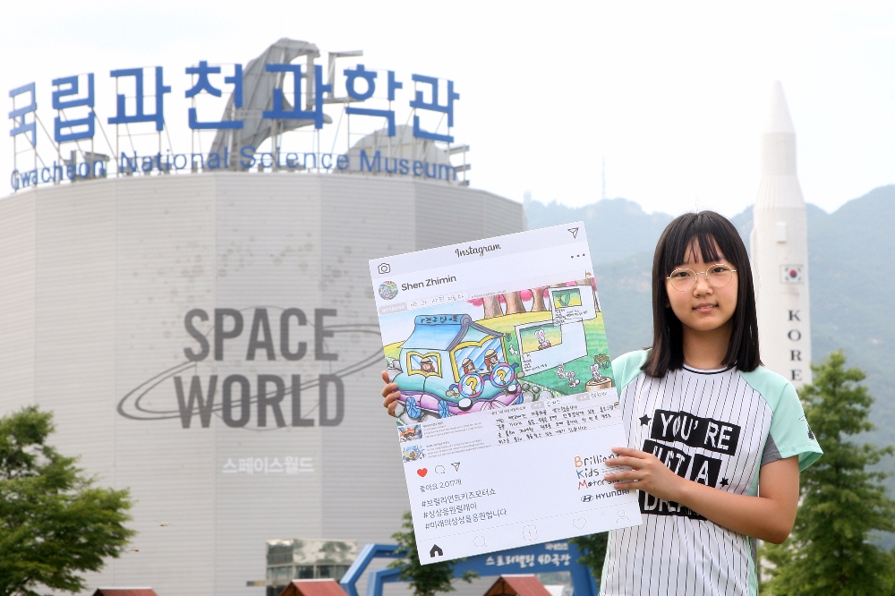 대상에 선정된 신지민 양(11세)이 ‘제2회 브릴리언트 키즈 모터쇼’가 열릴 국립과천과학관에서 ‘백과사전 자동차’ 그림 작품을 들고 있는 모습.(제공=현대자동차)
