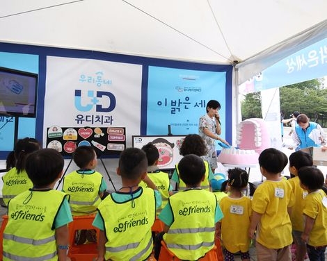 전영희 ㈜유디경영지원팀 차장이 아이들에게 구강모형을 이용하여 올바른 칫솔질 교육을 하고 있다(사진=유디치과)