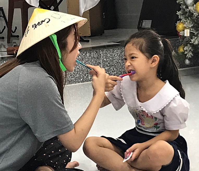 봉사단이 베트남 어린이들에게 구강모형을 이용해 위생교육을 실시한 후, 유디치과에서 후원한 구강용품을 올바른 칫솔질 교육을 하고 있다. (사진=유디치과)