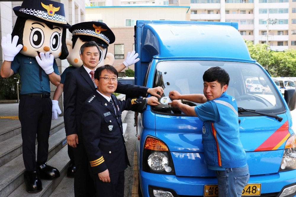 김홍근 동대문경찰서장과 진상훈 CJ대한통운 상무가 이재황씨 택배차량에 '포돌이 안심택배' 인증 스티커를 부착하고 있다. (사진=CJ대한통운)