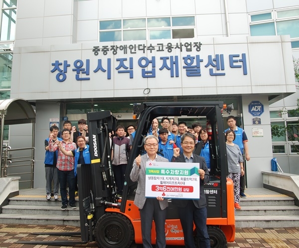 특수차량 전달식을 갖고 기념촬영을 하고 있다(앞줄 사진왼쪽 강명조 창원시직업재활센터장, 오른쪽 김용희 경남사회복지공동모금회사무처장). (사진제공=경남사회복지공동모금회)