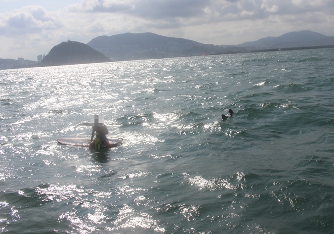 힘이 빠진 채 보드에 앉아 있는 K씨.(사진제공=부산해양경찰서)