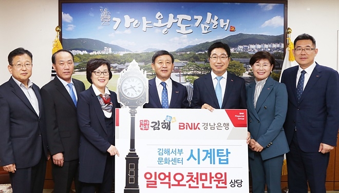 BNK경남은행 황윤철 은행장(사진 오른쪽 세번째)이 허성곤 김해시장에게 ‘(재)김해서부문화센터 시계탑 기증서’를 전달한 뒤 기념촬영하고 있다.(사진제공=BNK경남은행)