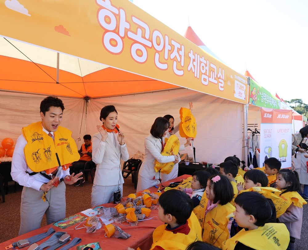 제주항공 객실승무원들이 10월25일 서울 여의도공원에서 열리고 있는 ‘2018 서울 안전 한마당’에서 ‘항공안전체험교실’에 참여한 어린이들에게 비상상황 발생시 산소마스크 및 구명복 착용방법을 가르쳐 주고 있다.(사진=제주항공)