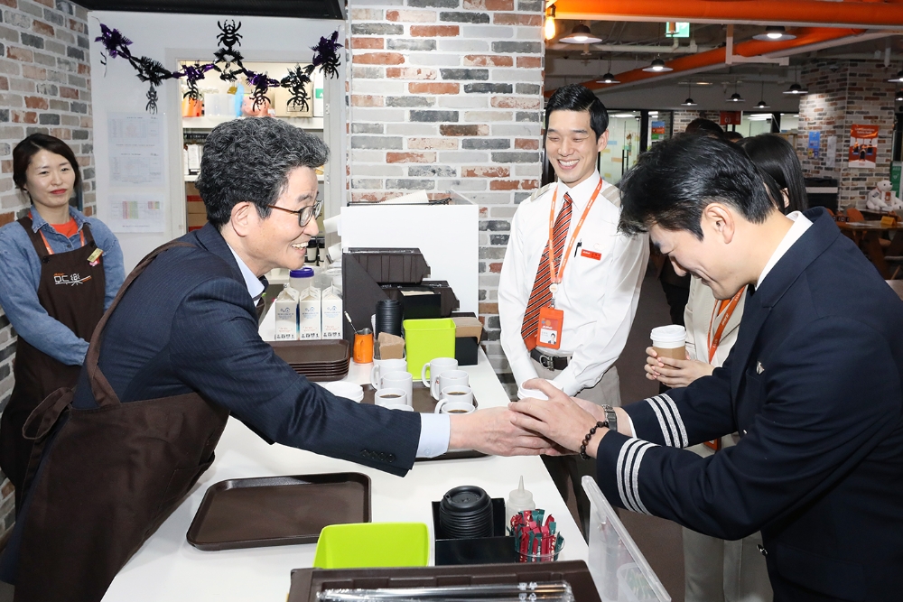 대통령 직속 일자리위원회 이목희 부위원장(사진 왼쪽)이 23일 오전 서울 강서구 김포국제공항 제주항공 라운지에 마련된 자회사형 장애인표준사업장 '모두락'에서 승무원들에게 커피를 건네고 있다. (사진=제주항공)