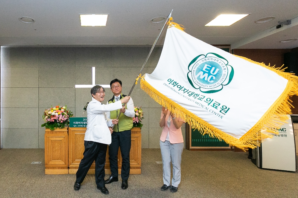 문병인 이화여자대학교 의료원장(사진 왼쪽)과 허창범 보건의료노조 이화의료원 지부장(사진 오른쪽)이 새롭게 만들어진 이화의료원기를 흔들고 있다. (사진=이화의료원)