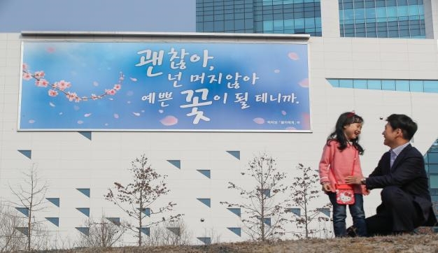 지난 16일 원주 혁신도시 본사 사옥 외벽에 ‘괜찮아, 넌 머지않아 예쁜 꽃이 될 테니까’ 글귀를 게시하였다. 이는 박치성 시인의 시 ‘봄이에게’에서 발췌하였으며 ‘행복 글판’ 글귀는 계절별로 교체된다. (사진=국민건강보험공단)
