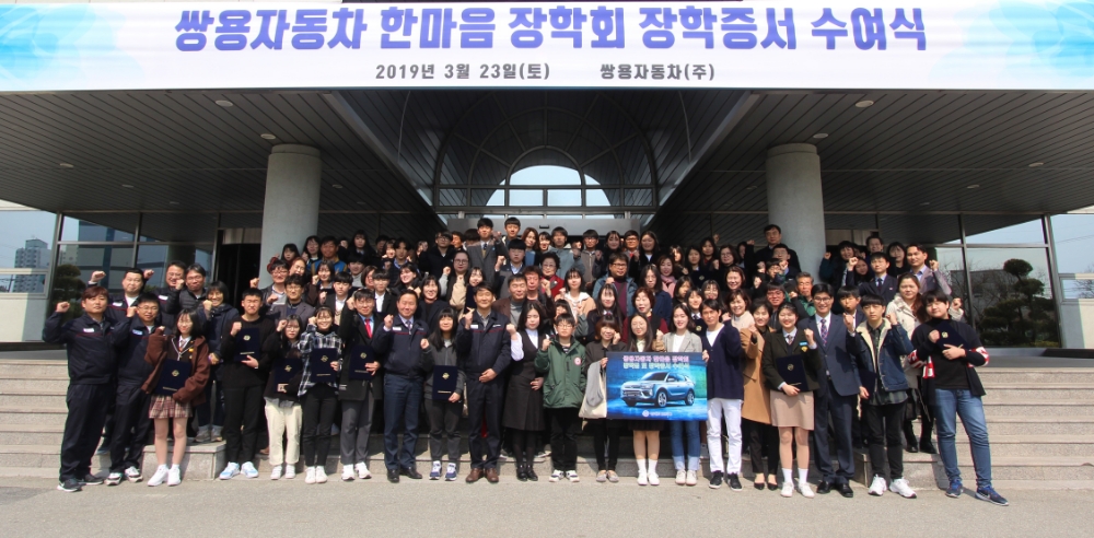 쌍용자동차 노무담당 박장호 상무(사진 첫째줄 왼쪽에서 여덟 번째), 쌍용자동차노동조합 강성원 수석부위원장(첫째줄 왼쪽에서 열 번 째)을 비롯한 한마음 장학회 관계자들과 장학생 및 가족들이 쌍용자동차 본사 건물 앞에서 기념촬영을 하고 있다.(사진=쌍용자동차)