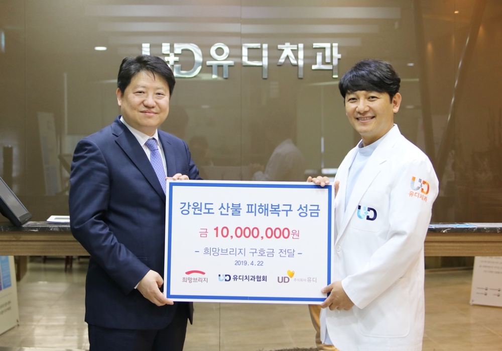 진세식 유디치과 협회장(우)과 김종명 ㈜유디 사장(좌)이 강원도 산불 피해복구 성금을 전달하고 있다. (사진=유디치과)