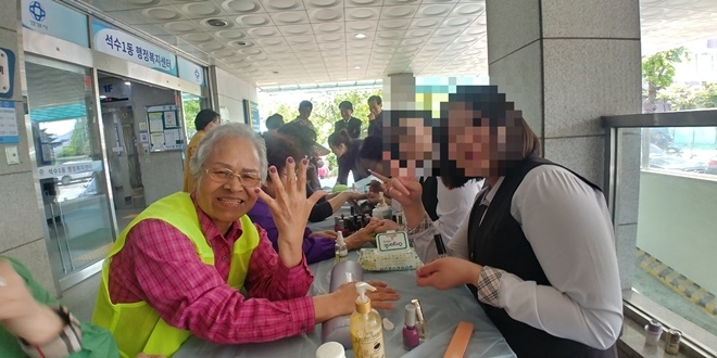 어른신이 네일아트 한 손을 보여주며 즐거워하고 있다.(사진제공=정심여자중고등학교)