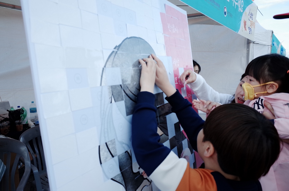 시민들이 스티커를 판넬에 붙여 한부모 가족의 모습을 완성하는 한샘 부스 행사에 참여하고 있다..(사진=한샘)