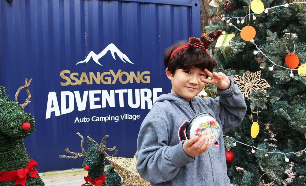 어린이 참가자가 선물을 받아 들고 2020 소망트리 앞에서 포즈를 취하고 있다.(사진=쌍용자동차)