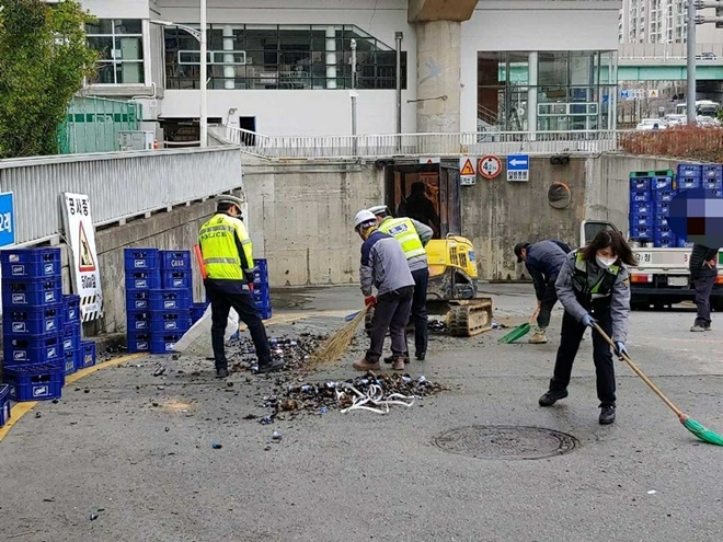 깨진 맥주병과 박스를 치우는데 경찰관들이 돕고 있다.(사진제공=부산경찰청)