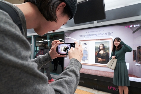서울 지하철 6호선 공덕역에 마련된 세계 최초 5G기반 문화예술 공간 ’U+5G 갤러리’에 방문한 고객이 ‘U+AR’ 앱으로 작품을 체험하고 감상하는 모습. 사진=LG유플러스