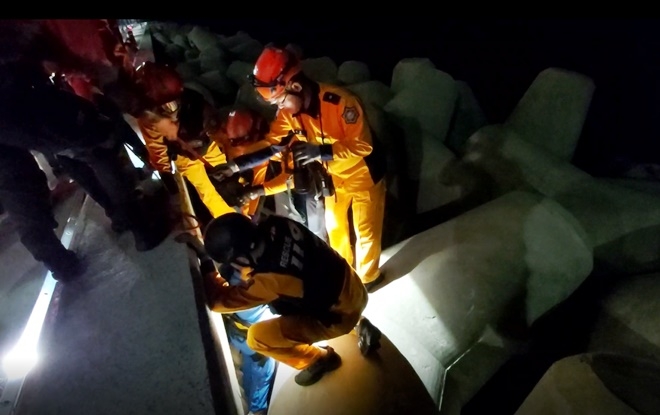 테트라포드 사이에 빠진 요구조자를 구조하고 있다.(사진제공=부산소방재난본부)