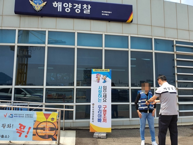 해경이 구명조끼를 대여한 시민에게 조끼를 입히고 있다.(사진제공=부산해양경찰서)
