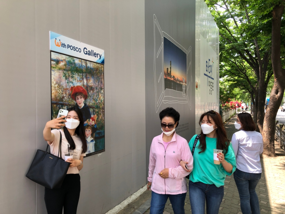 시민들이 포스코건설이 시공중인 서울 신길3구역 현장 펜스에 설치된 With POSCO 갤러리 앞에서 사진을 찍으며 즐거워하고 있다.(사진=포스코건설)