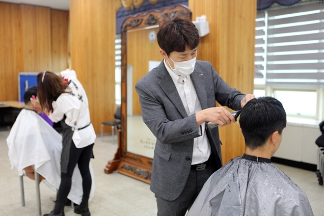 미용사 이혜동 씨가 재능기부로 이발봉사를 하고 있다.(사진제공=부산해양경찰서)