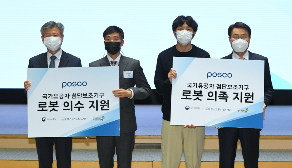 최정우 포스코 회장과 박삼득 국가보훈처장이 국가유공자에게 첨단보조기구 전달하고 기념촬영을 하고 있다. (왼쪽부터 박삼득 국가보훈처장, 나형윤 국가유공자, 박주남 국가유공자, 최정우 포스코회장).(사진=포스코)