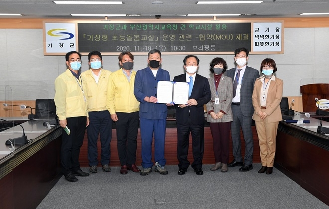 19일 오전 10시 30분 기장군청 브리핑룸에서 기장군은 부산시교육청과 전국 최초로 365일 연중무휴로 운영하는 ‘기장형 초등 돌봄교실’ 운영을 위한 협약을 체결하고 오규석 기장군수(왼쪽네번째)와 김석준 부산교육감(우측네번째)이 협약서를 내보이며 기념촬영.(사진제공=부산 기장군)