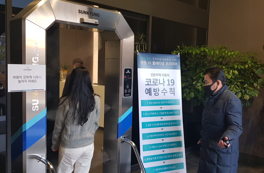 지난 18일 오픈한 '쌍용 더 플래티넘 프리미어' 견본주택을 찾은 방문객들이 입장 전 터널형 전신 소독기를 통과하는 모습.(사진=쌍용건설)