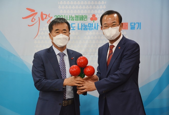 강기철 경남사회복지공동모금회장이 한철수 창원상의회장(사진왼쪽)에게 사랑의 열매를 달아주고 기념촬영.(사진제공=경남사랑의열매)