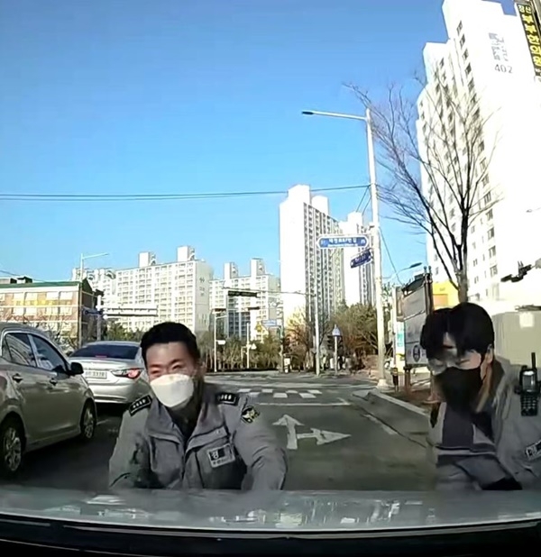 저절로 내려온 빈 택시를 몸으로 막고 있는 1기동대 이원빈 경사, 김창환 순경.(사진제공=부산경찰청)